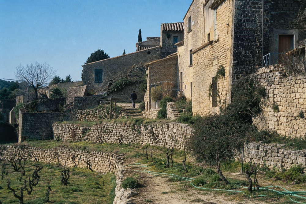 Dry-stone terraced vineyards on a Valpolicella hillside with a small stone hamlet, no text, no logos, no people
