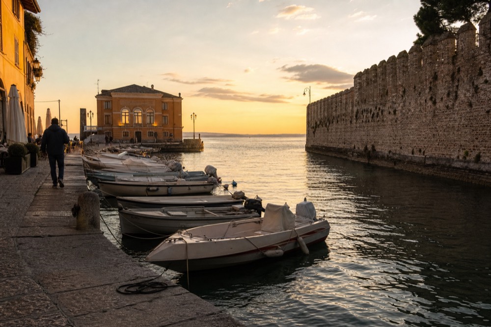 Lakeside walls and harbour of a Lake Garda village at golden hour, no text, no logos, no people