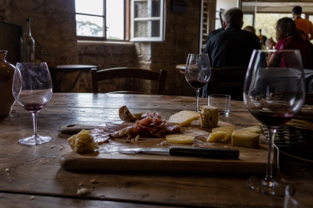A tasting platter with cheese, cold cuts and glasses of wine on a rustic table, no text, no logos, no people
